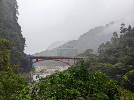 Photo for Taroko, Taiwan - 11.26.2022: Red metal Shakadong Bridge over Liwu River connecting tunnels in a mist with staircase to Shakadong Trail in maintenance and mountains at the back before 403 earthquake - Royalty Free Image