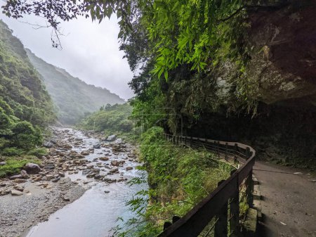 Photo for Taroko, Taiwan - 11.26.2022: Empty Shakadang Trail crawls along cliffs and trees with Liwu River running on the side in a mist during the pandemic before 403 earthquake on a rainy day - Royalty Free Image
