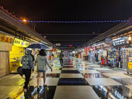 Photo for Hualien, Taiwan - 11.24.2022: A few customers browsing the market stalls in Dongdamen Night Market in Hualien during the pandemic on a rainy night - Royalty Free Image