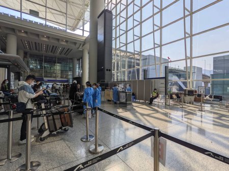 Photo for Hong Kong International Airport - 09.06.2022: Newly arrived passengers waiting at the arrival hall with luggage for shuttles to transfer to specific hotels for quarantine during the pandemic - Royalty Free Image