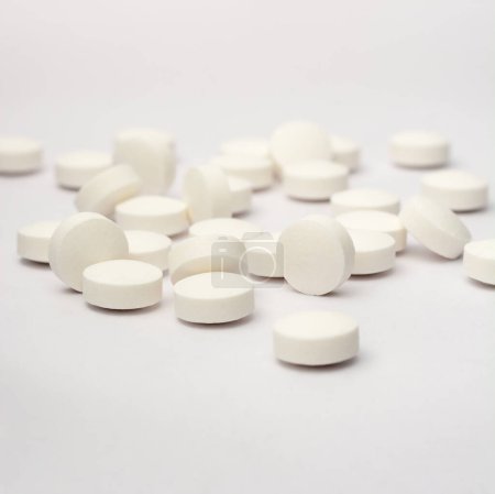 weiße runde Pillen oder Tabletten auf weißem Hintergrund verstreut, Medikamente mit weichem Fokus und Kopierraum