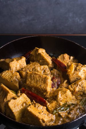 Photo for Cooking jackfruit curry dish, tempering with oil and coconut milk, classic sri lankan vegetarian dish on a pan, closeup view - Royalty Free Image
