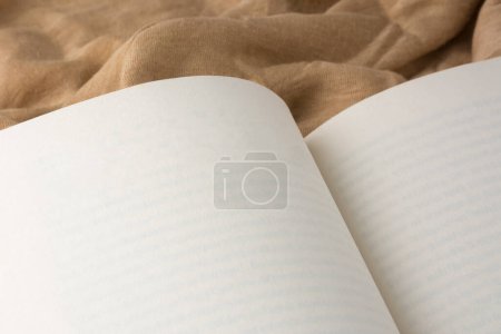 Téléchargez les photos : Livre blanc ouvert sur un fond de tissu brun clair, modèle de maquette broché avec espace de copie - en image libre de droit