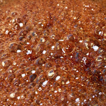 Téléchargez les photos : Gros plan des bulles lorsque le sucre bouillant se transforme en caramel, abstrait en plein cadre de la caramélisation, mise au point sélective - en image libre de droit