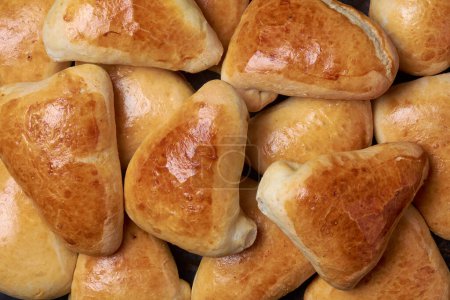 curry buns, type of savory bread that is filled with mixture of curry sauce and vegetables, close-up of golden brown and slightly crispy popular snack in full frame, food background