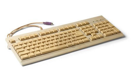 old used computer keyboard with ps/2 connector or port, beige color early days mechanical computer input device, isolated white background with shadows
