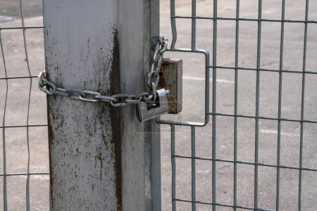 fence: pole and padlock with chain to a fence with electro-welded metal grating in stainless steel. the grill is made with a resistant and solid structure which increases the safety of the premises.