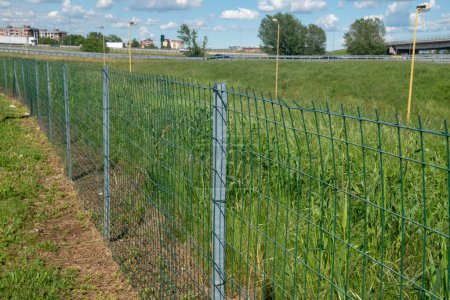 Grenzzaun auf einem Feld mit verzinktem Stahlmast und elektrogeschweißtem rechteckigem Maschengewebe. Grundstücksgrenzen sind mit Masten und Netzen abgegrenzt.