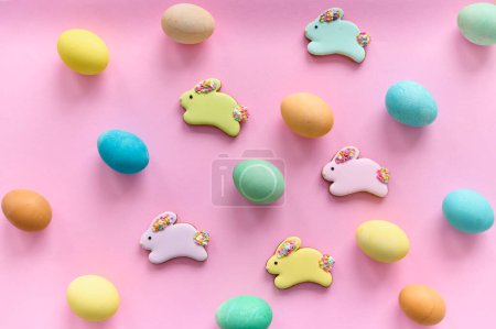 Photo for Colored easter eggs  with a chocolate bunny cookies on a pink background - Royalty Free Image