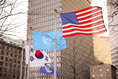 Die US-Flagge steht für Demokratie, Freiheit und Patriotismus. Die UN-Flagge symbolisiert globale Zusammenarbeit und Frieden. Die koreanische Flagge symbolisiert Gleichgewicht, Harmonie und Einheit. 