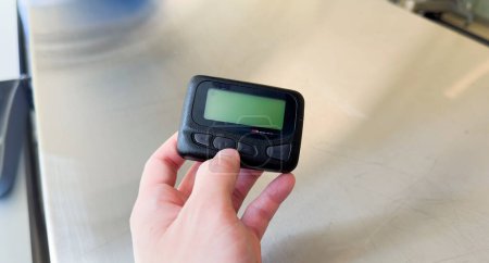 Photo for Pager is a small wireless device that receives and displays numeric or text messages, symbolizing the era of technological advancements in communication and transition from analog to digital device - Royalty Free Image