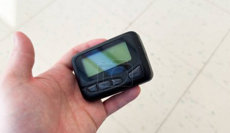 Photo for Pager is a small wireless device that receives and displays numeric or text messages, symbolizing the era of technological advancements in communication and transition from analog to digital device - Royalty Free Image