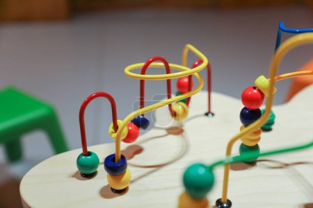 klassisches Perlen-Labyrinth-Spielzeug mit bunten Perlen an Drähten, die Kinder bewegen können. Symbolisiert die frühkindliche Entwicklung der Motorik und der Hand-Auge-Koordination sowie das Konzept von Ursache und Wirkung