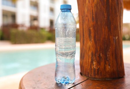 Foto de Botellas de plástico dispersas alrededor de la piscina y la playa representan el impacto negativo de la actividad humana en el medio ambiente. La contaminación causada por botellas de plástico de un solo uso afecta al océano - Imagen libre de derechos