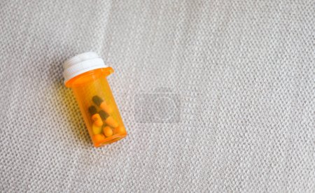 Foto de Frasco redondo de color naranja lleno de pastillas que representan la medicina y la salud. Simboliza la curación, el tratamiento y el alivio de la enfermedad o el dolor - Imagen libre de derechos