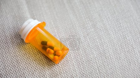 Téléchargez les photos : Bouteille ronde orange remplie de pilules représentant la médecine et la santé. Symbole de guérison, de traitement et de soulagement de la maladie ou de la douleur - en image libre de droit