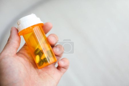 Foto de Frasco redondo de color naranja lleno de pastillas que representan la medicina y la salud. Simboliza la curación, el tratamiento y el alivio de la enfermedad o el dolor - Imagen libre de derechos