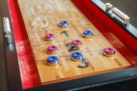 Shuffleboard ist ein Präzisions- und Strategiespiel, bei dem die Spieler beschwerte Scheiben auf einem schmalen Spielfeld hinunterschieben, um in Punktebereiche zu gelangen. Der Sport steht für das Streben nach Genauigkeit und Geduld