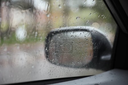 Photo for Car window covered in raindrops symbolizes the beauty and tranquility of nature. The water droplets on the glass and the sound of rain on the roof create a calming ambiance - Royalty Free Image