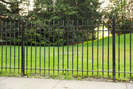 Photo for Black metal fence symbolizes boundaries, protection, and security. It represents the division between spaces, the need for privacy, and the sense of safety it provides - Royalty Free Image