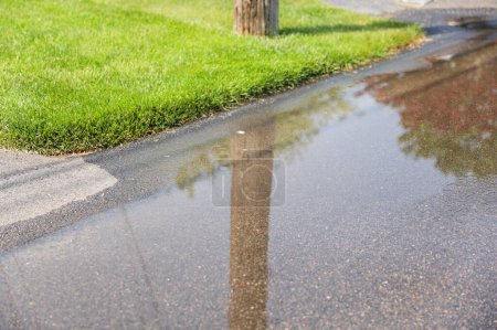 Wasserpfütze auf der Straße nach Regen spiegelt Erneuerung, Ruhe und die Schönheit einfacher Momente der Natur wider