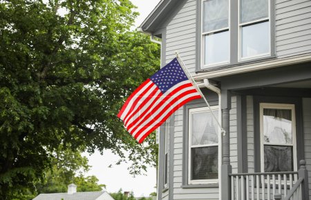 Photo for American flag waving in front of house - Royalty Free Image