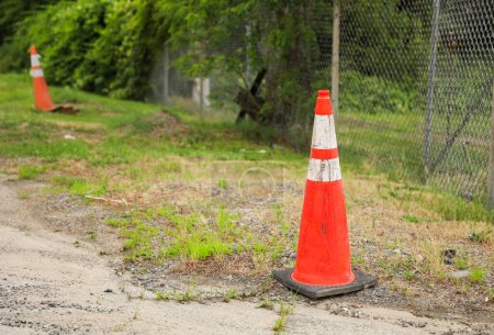 cônes de construction orange vif disposés en ligne, symbolisant la sécurité, la prudence et les progrès continus dans les projets de construction et d'infrastructure. Les cônes représentent des barrières temporaires
