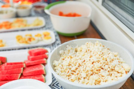 Photo for Potluck spread of fresh veggies, fruits, and dips, complemented by crunchy chips, popcorn, and eggs, symbolizing diversity, nourishment, and shared experiences - Royalty Free Image