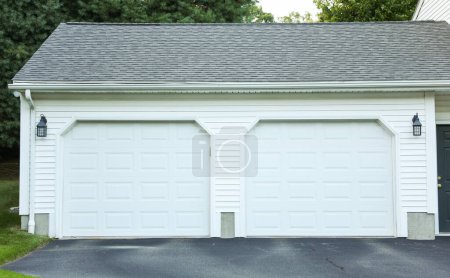 front of the garage with white brick garage and a blue door.