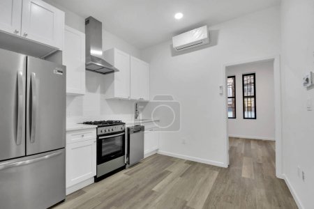 Téléchargez les photos : Intérieur de la cuisine moderne avec murs blancs et plancher en bois. - en image libre de droit