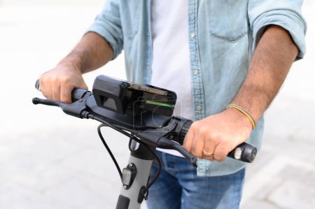 Photo for Anonymous male in jeans and denim shirt riding electric scooter on paved street of city during weekend day - Royalty Free Image