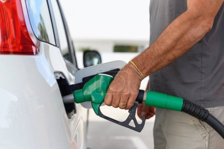 Téléchargez les photos : Gros plan d'un homme utilisant une pompe à essence pour ravitailler son véhicule pendant une crise énergétique - en image libre de droit