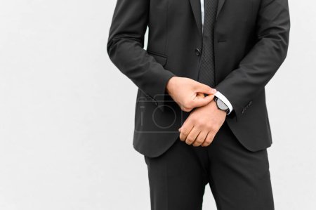 Téléchargez les photos : Entrepreneur masculin méconnaissable en costume élégant tenant la main dans la poche tout en se tenant sur fond blanc. contenu commercial - en image libre de droit