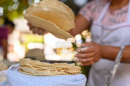 Foto de Cultivo anónimo mujer hispana poniendo apetitosos panes mexicanos fritos en la pila en el campo de verano en México - Imagen libre de derechos