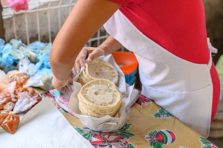 Photo for High angle of anonymous female chef in apron standing at table and wrapping tasty Mexican flatbreads into napkins in Mexico - Royalty Free Image