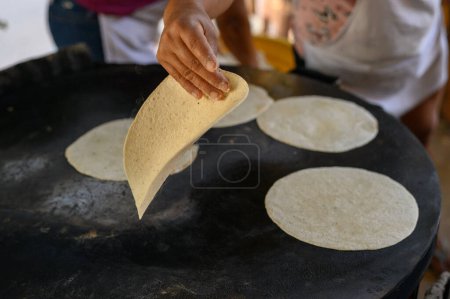 Téléchargez les photos : Angle élevé de cuisson anonyme femme cuisinière tortillas faites à la main sur la plaque de cuisson au stand du marché - en image libre de droit