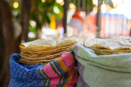 Foto de Enfoque suave de pilas de sabroso pan plano chapati de maíz blanco en bolsas de colores en la calle en México contra el fondo borroso - Imagen libre de derechos
