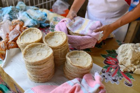 Téléchargez les photos : Grand angle de culture cuisinier anonyme debout près de tortillas fraîchement empilées sur le comptoir dans un magasin mexicain typique - en image libre de droit