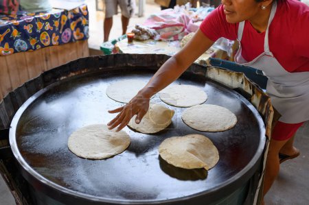 Foto de Desde arriba de la cosecha irreconocible cocinera mexicana poniendo masa en la plancha caliente mientras hornea sabroso chapati flatbread en la calle - Imagen libre de derechos
