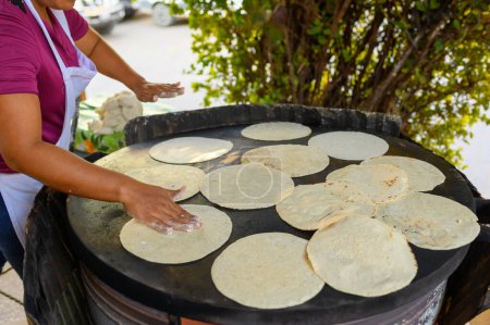 Photo for High angle of crop anonymous Mexican female cook in apron preparing delicious traditional corn tortillas on big griddle on street - Royalty Free Image