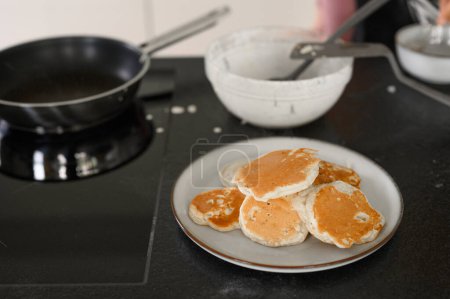 Foto de Alto ángulo de apetitosos panqueques de desayuno en el plato junto a la sartén colocado en la mesa en la cocina - Imagen libre de derechos