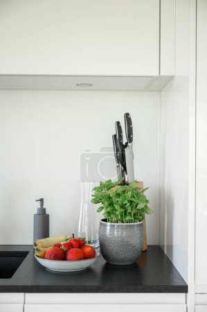 Foto de Cuenco con frutas y verduras frescas colocado en la mesa en la moderna cocina blanca en casa - Imagen libre de derechos