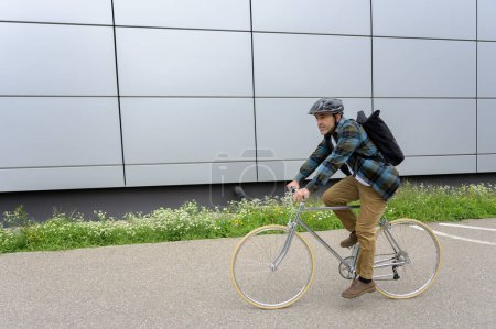 Téléchargez les photos : Vue latérale de la jeune femme en vêtements décontractés et casque vélo d'équitation sur route asphaltée en ville - en image libre de droit