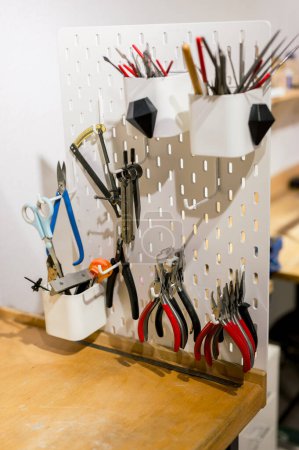 Foto de Diferentes tipos de herramientas de joyería colgando en la pared en atelier, concepto de negocio - Imagen libre de derechos