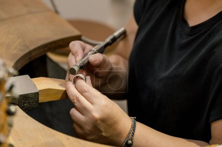 Photo for Side view hands of unrecognizable woman sitting at goldsmith workspace, grinding ring and working in jewelry atelier. business concept - Royalty Free Image