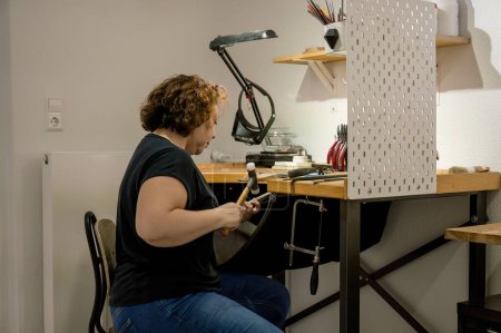 Foto de Vista posterior de la artesana adulta enfocada sentada en el espacio de trabajo y trabajando en el taller de joyería. concepto de negocio - Imagen libre de derechos