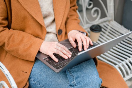 Photo for High angle of crop anonymous female freelancer sitting outside with laptop and working on project, freelance work - Royalty Free Image