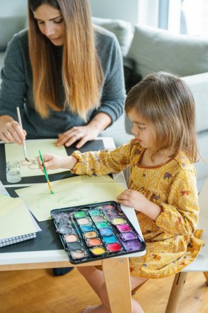 Foto de Una madre y su hijo pasan tiempo de calidad juntos, uniéndose a través de una divertida y creativa sesión de pintura en casa - Imagen libre de derechos