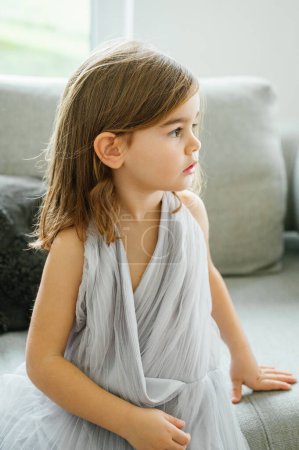 Photo for A young concentrated girl lost in a book, lounging comfortably on a couch, enjoying a quiet moment of reading, leaning on sofa, child and family concept - Royalty Free Image