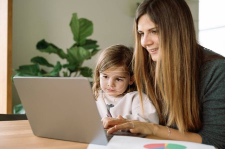 Photo for Young working mother with daughter in home office - Royalty Free Image